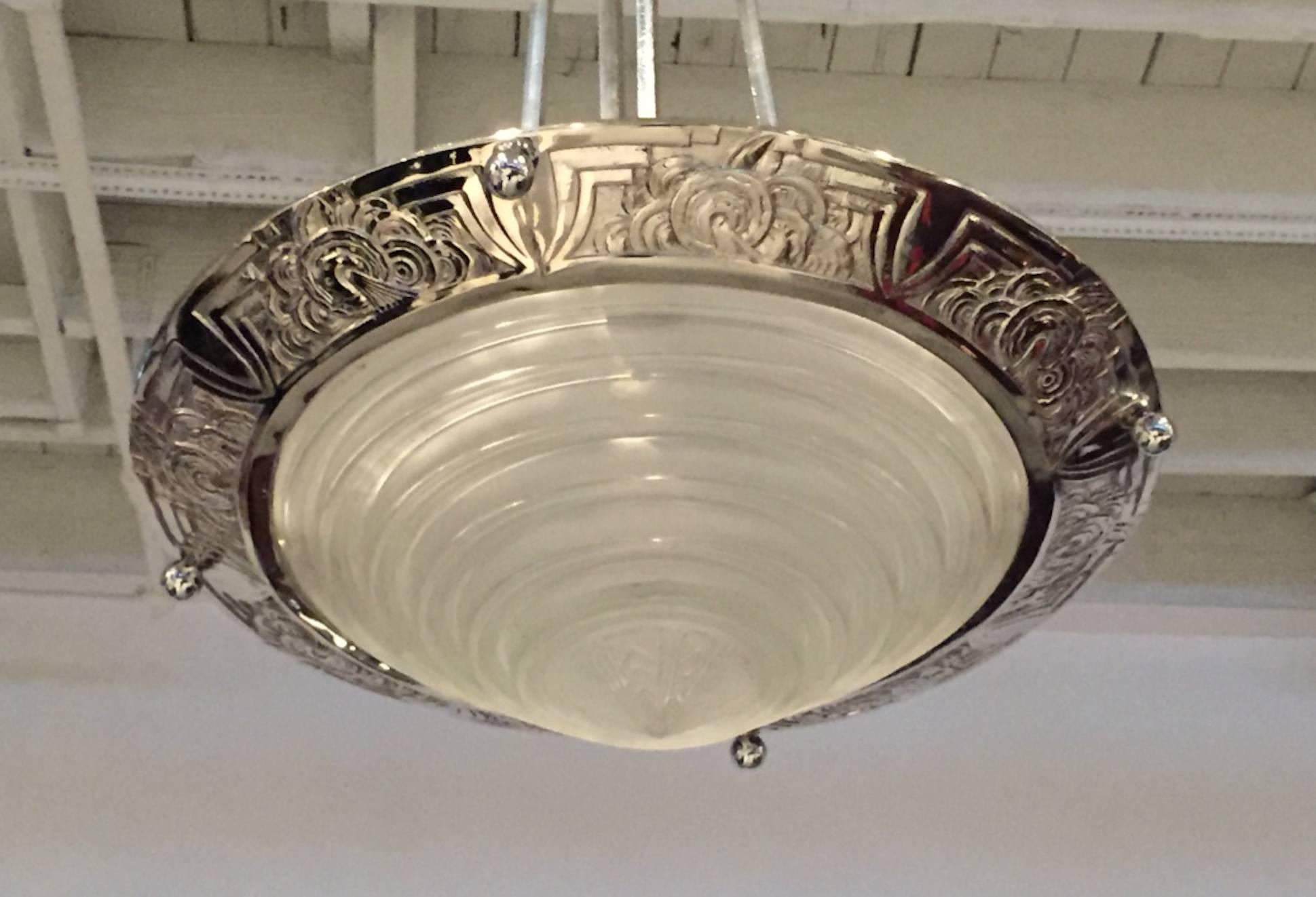 A stunning French Art Deco chandelier signed by G. Leleu. With a beautiful center bowl in clear frosted molded glass with ribbed and geometric motif. Polished details on a nickel bronze frame with geometric design and beautiful matching ceiling