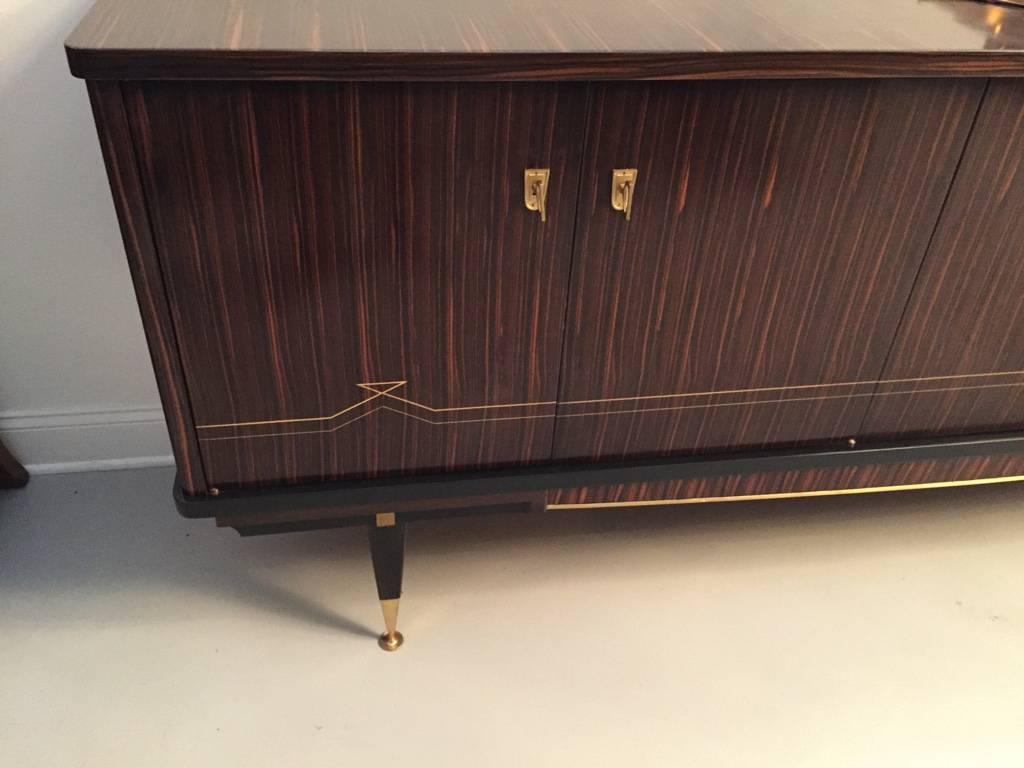 Stunning French Art Deco Macassar Ebony sideboard. Having a central cabinet door that opens to reveal a dry bar. With hardware that accents the buffet beautifully.