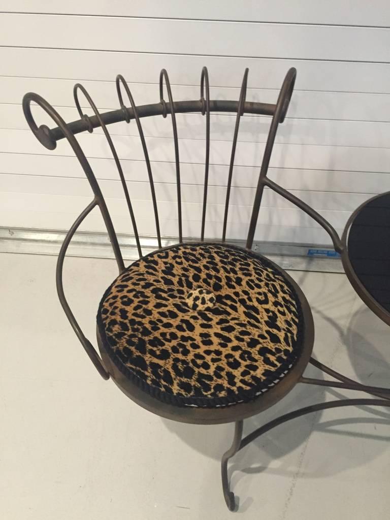 Teetisch aus Metall mit zwei Stühlen mit Leopardenmuster-Kissen und Tisch mit Marmorplatte.