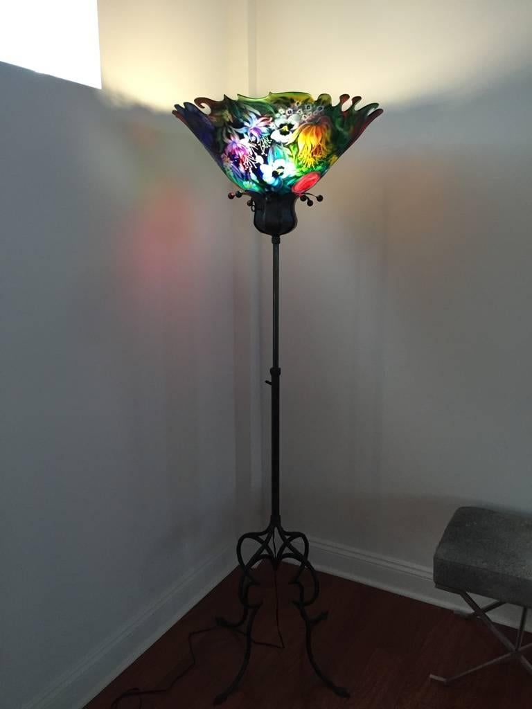 This gorgeous original Ulla Darni floor lamp is reverse painted on glass with hand-forged iron work having an adjustable base. Ulla starts with a blank glass surface to paint on. She uses vibrant colors that pop off the glass, making it feel like