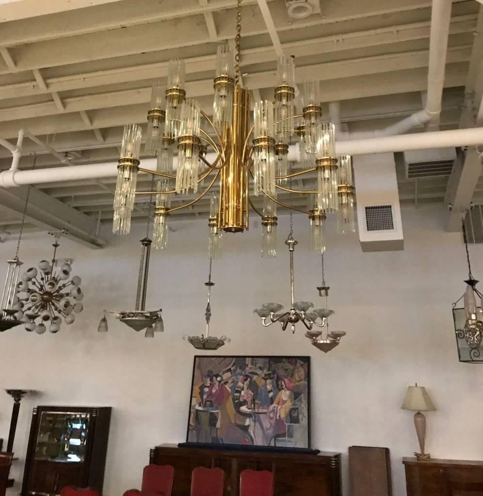 This incredible Italian Mid-Century chandelier is by Gaetano Scolari. Intertwining brass arms form this breath taking chandelier with plenty of light to fill any room. Each glass rod sits on its own forming a ring around the bulb. Any amount of