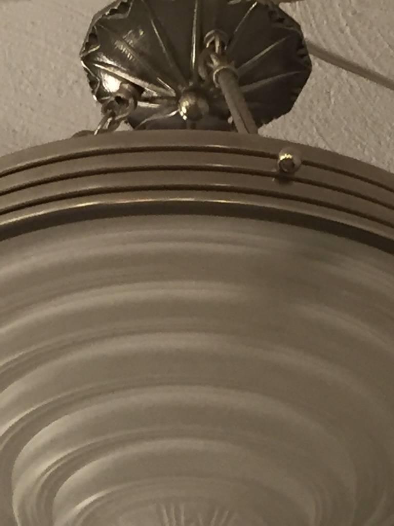 A stunning French Art Deco chandelier signed by G. Leleu. With a beautiful center bowl in clear frosted molded glass with ribbed and geometric motif. Polished details on a nickel bronze frame. Re-plating upon request.
