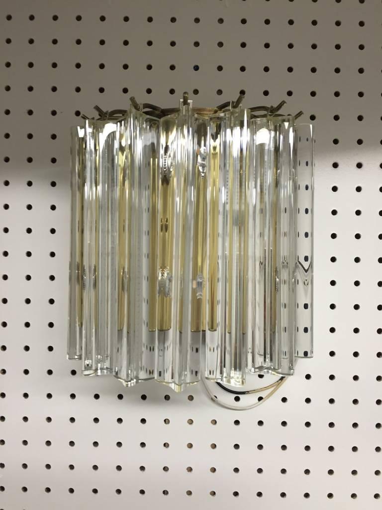 Stunning  Italian Mid-Century Modern sconces by Venini. Having a brass frame and beautiful glass prisms. Each of the prisms are solid glass, measuring 8 inches each. Three available. 