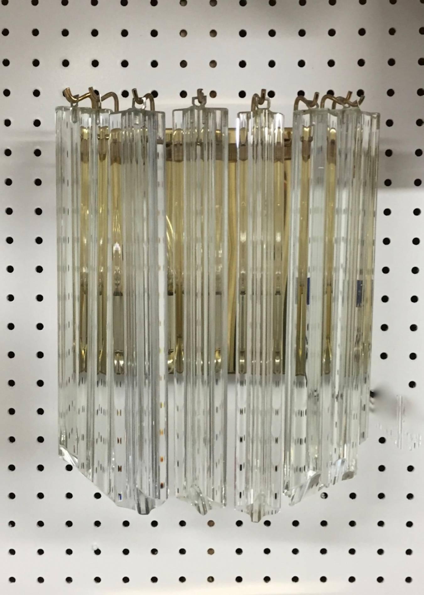 Stunning Italian Mid-Century Modern sconces by Venini. Having a brass frame and beautiful glass prisms. Each of the prisms are solid glass, measuring 11 inches each. Three available. 