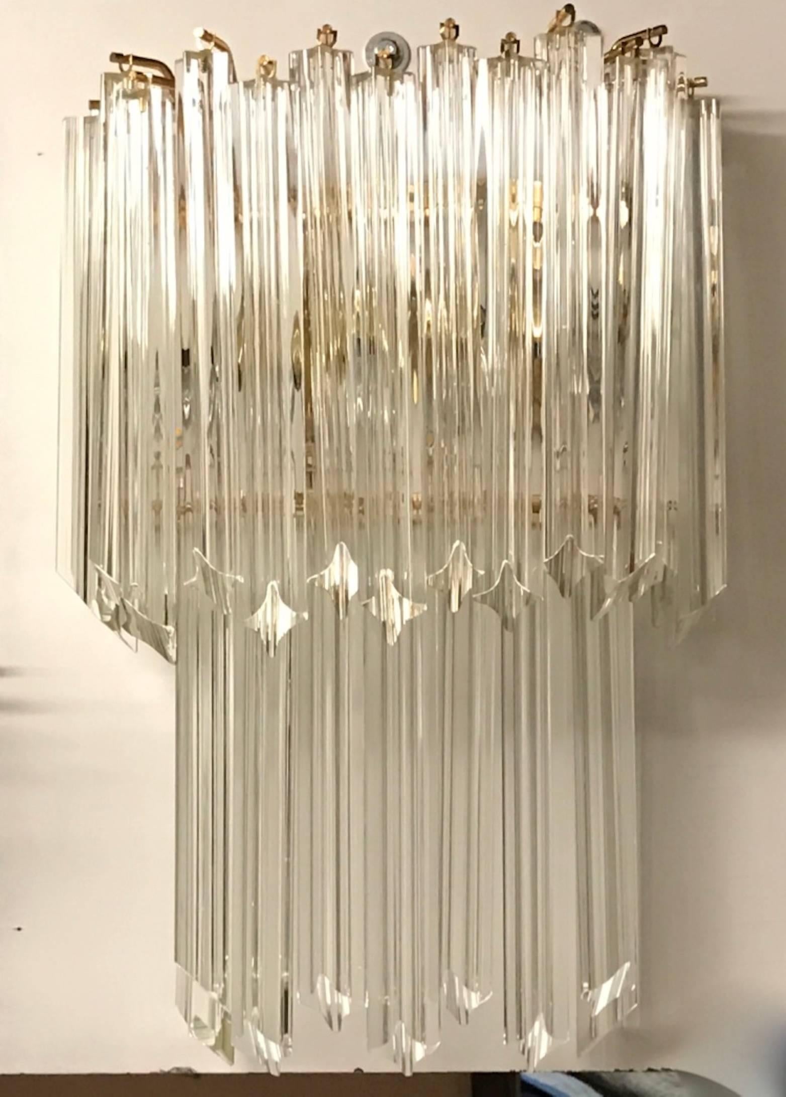 Stunning pair of Italian Mid-Century Modern sconces by Venini. Having a brass frame and beautiful glass prisms. Each of the prisms are solid glass, measuring 11 inches each. Giving off beautiful amount of light.