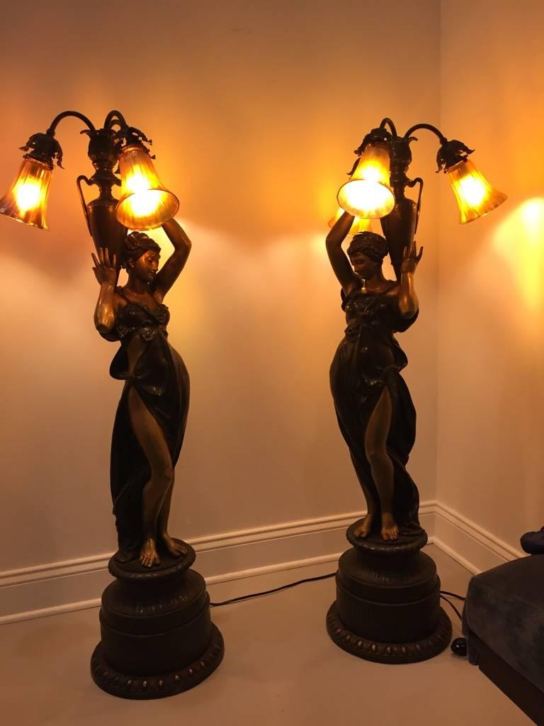 This pair of stunning large bronze figural women 'torchere' lamps are each standing with both hands holding water jugs. The attention to detail is absolutely fantastic and these bronze figures are set upon attractive classical style bronze bases.