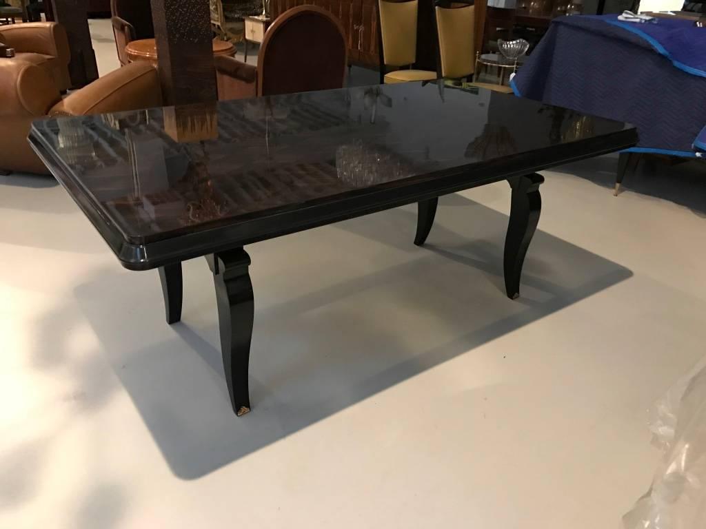 Stunning French Art Deco dining table with a high French polish finish. Having spectacular inlay and beautiful black lacquer legs with brass hardware to accent the wood beautifully. Gorgeous Deco Details.