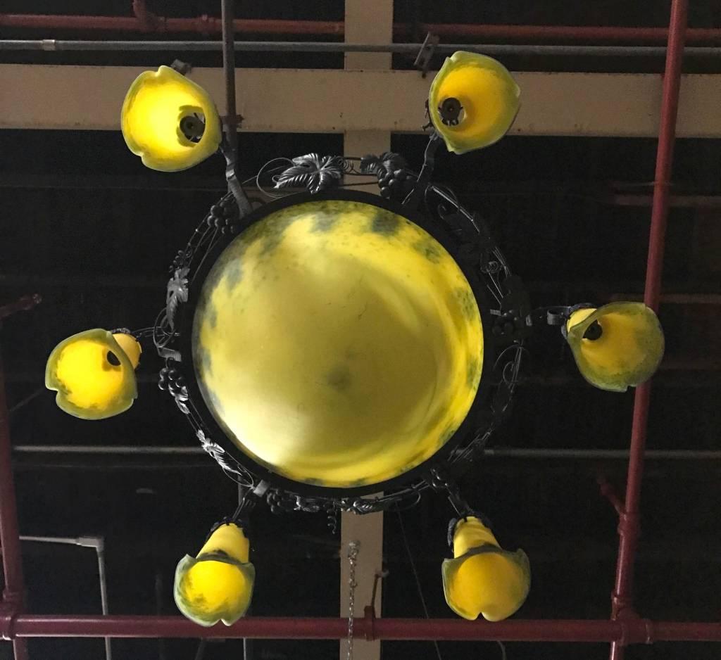 French Art Deco chandelier. Having a center glass bowl with six surrounding tulips in yellow and black colored glass. With floral details on the frame. Re-plating upon request.