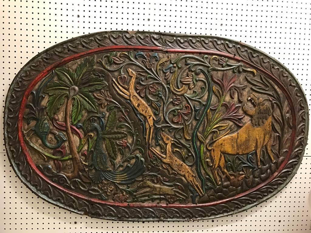 Carved wood plaque depicting animals. Having exotic animals including birds, lions and gazelles.