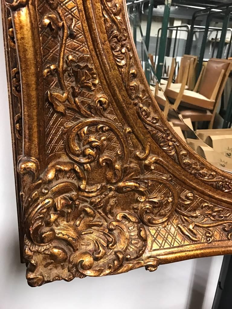 Gilt wood mirror with hand-carved ornate details. Having beveled mirror.