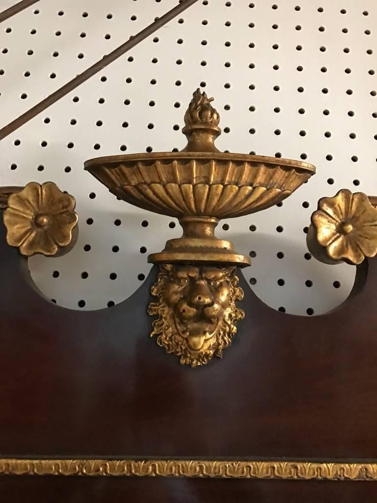 Superbe miroir en bois doré en acajou. Avec des détails en bois doré représentant un lion sur le dessus et un motif floral sur les côtés.