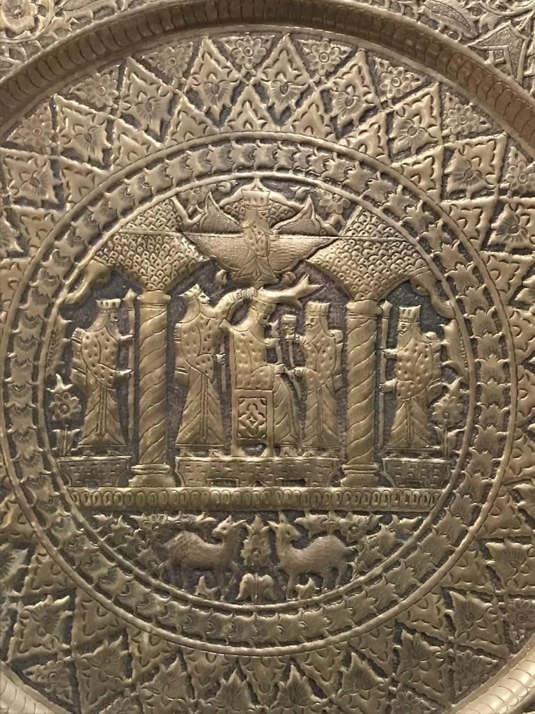 Wandteller mit dem Motiv von Königen und Königshäusern. Der Teller ist bronzefarben und hat durchgehend ein geometrisches Muster.