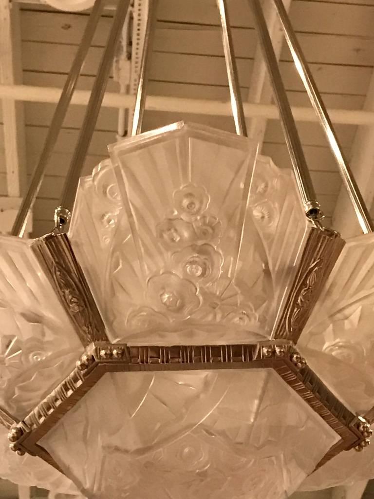 Stunning French Art Deco chandelier signed by J Robert. With beautiful center bowl and six clear frosted glass outer panels with geometric and floral motif. Having a cast bronze frame and ceiling plate with geometric motif.