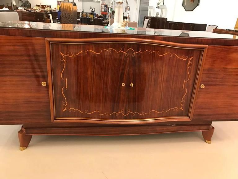 Stunning French Art Deco palisander Brazilian rosewood side board. Having gorgeous marquetry and black glass top. The brass hardware accents the wood beautifully. The interior is finished in sycamore.