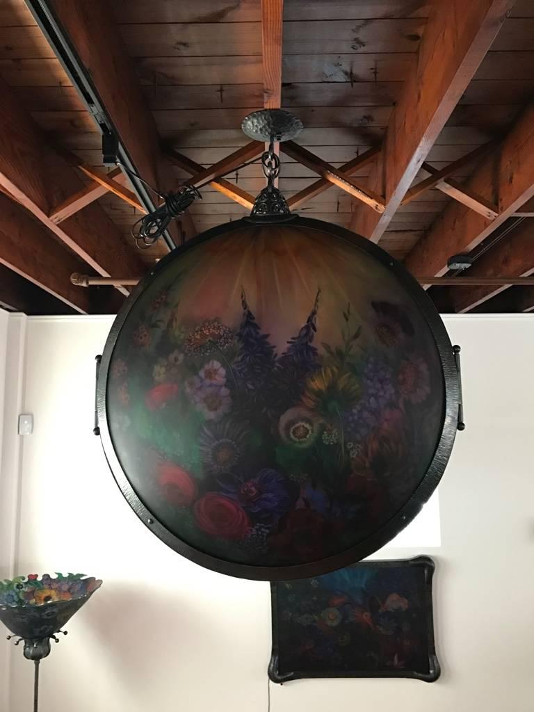 This gorgeous original Ulla Darni 32 inch locket chandelier is reverse painted on glass with hand-forged iron work. The chandelier hangs like a locket with glass on both sides of the chandelier. The colors are very vibrant. This truly is a one of a