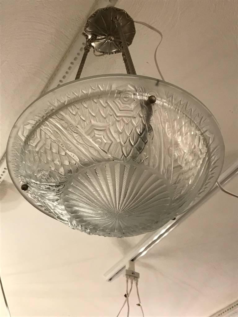 A French Art Deco pendant designed by the French artist “Schneider“. Clear frosted molded glass shade with intricate flowers and geometric polished motif details held by three rods with a matching canopy in Nickel finish. Pendant can be re-plated