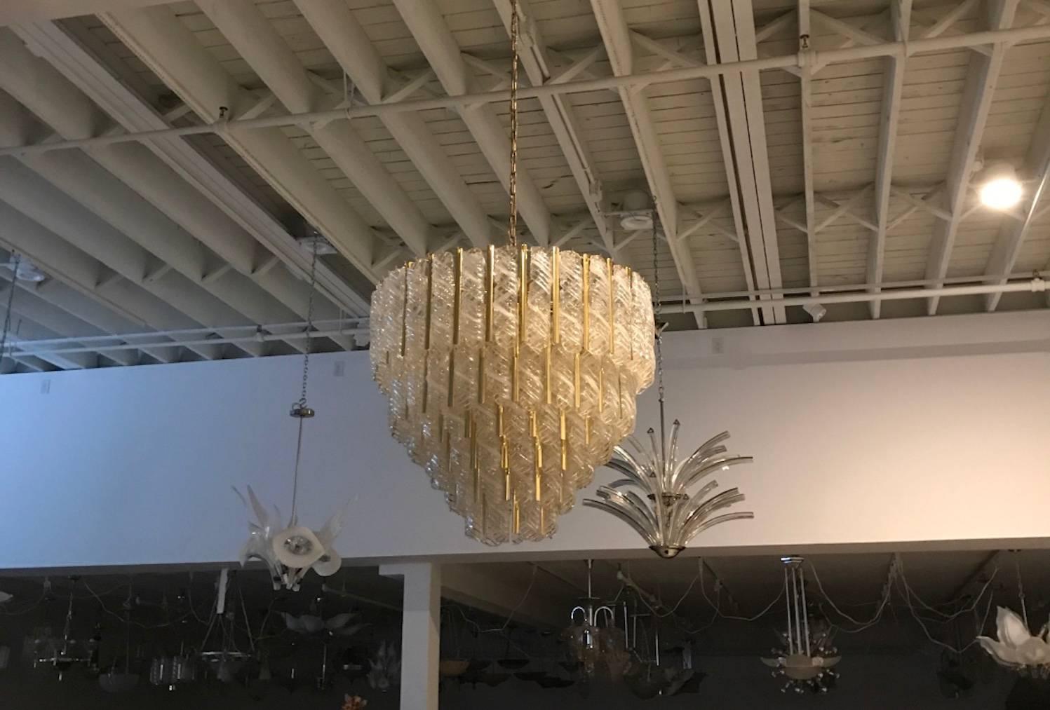 Stunning Italian Mid-Century Modern round six-tiered chandelier by Mazzega. 
Each piece of glass is handblown measuring 10 inches. The glass hangs from hooks onto a brass frame, as pictured. In-between each glass their is a gold metal divider. Any