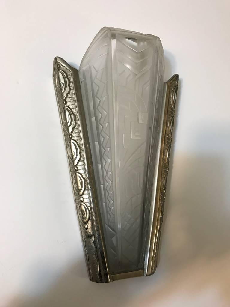 Stunning French Art Deco sconce by P. Maynadier. With clear frosted glass shade having intricate geometric motif details throughout. The shade is held by a sterling silvered bronze geometric design frame. Re plating upon request.