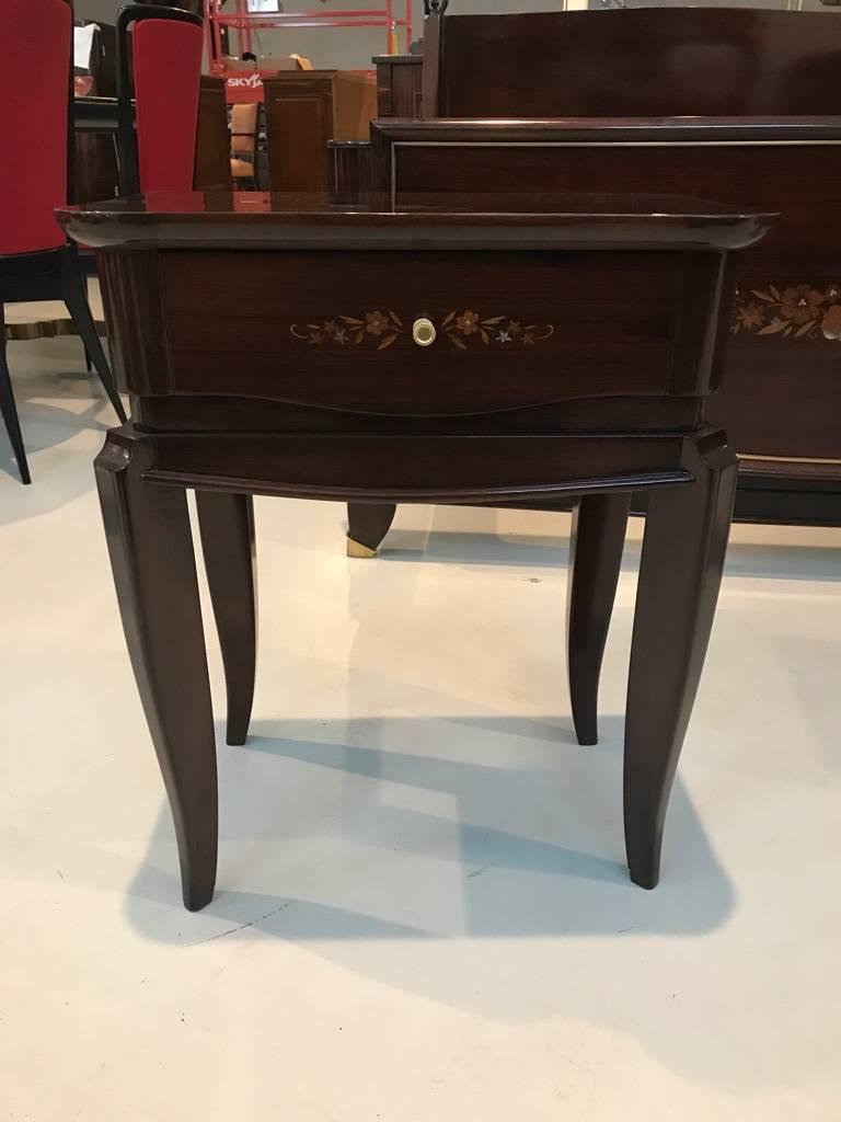 Stunning pair of French Art Deco nightstands. Having beautiful mother-of-pearl inlay forming a floral motif with brass hardware, which accents the beauty of the wood. Matching armoire.