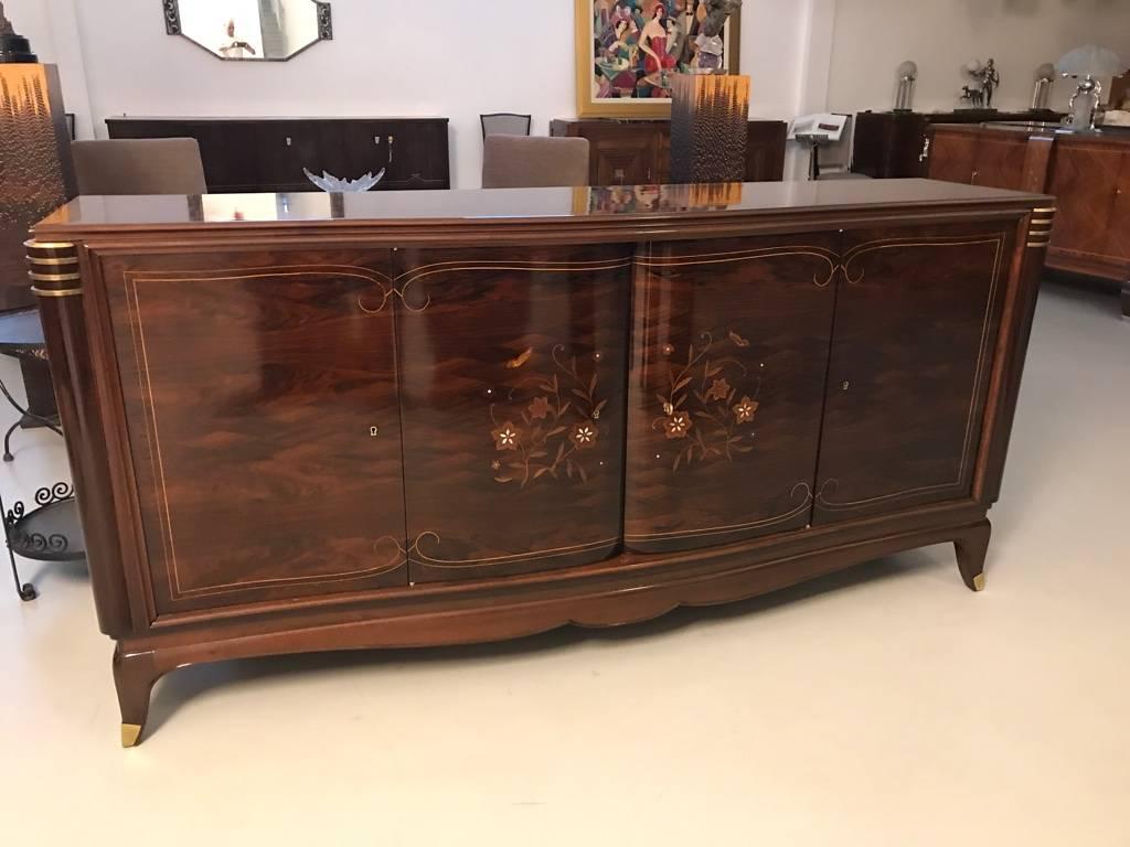 Stunning French Art Deco four-door sideboard in the style of Jules Leleu. With beautiful rosewood and mother-of-pearl inlay along with stunning marquetry. The middle doors open to reveal a bank of draws while the outer doors reveal shelfs. Having