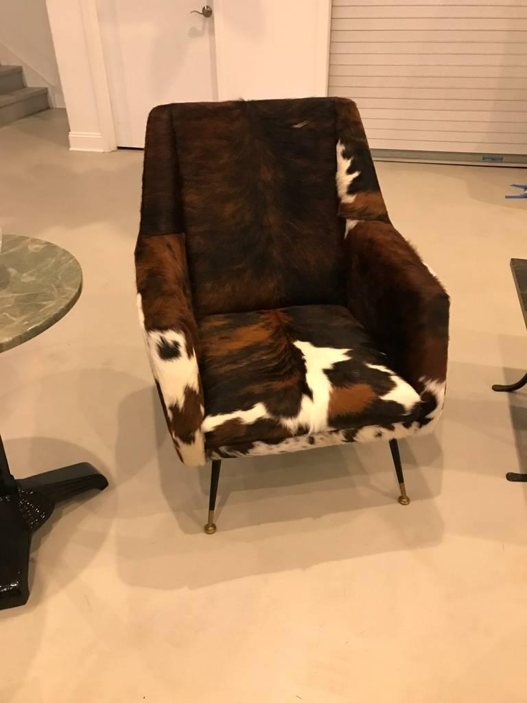A pair Italian Mid-Century Modern club chairs reupholstered in cow hide, circa 1960. These are great for any room and are extremely comfortable. The cowhide is in amazing condition.