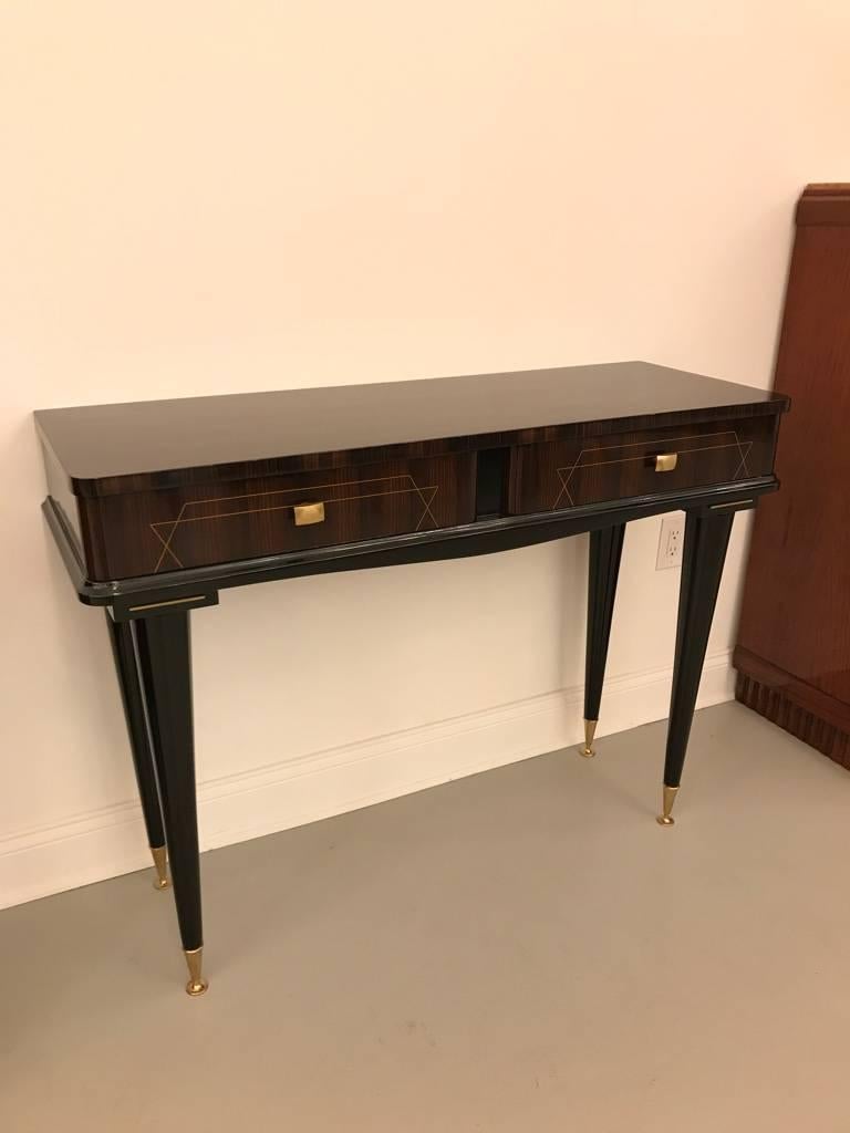 French Art Deco exotic Macassar ebony console table, circa 1940s. Having  Black lacquer legs, brass toe caps. With two draws having beautiful marquetry inlay. High gloss lacquer finish. Can also be used as a desk. Comes with glass top. 