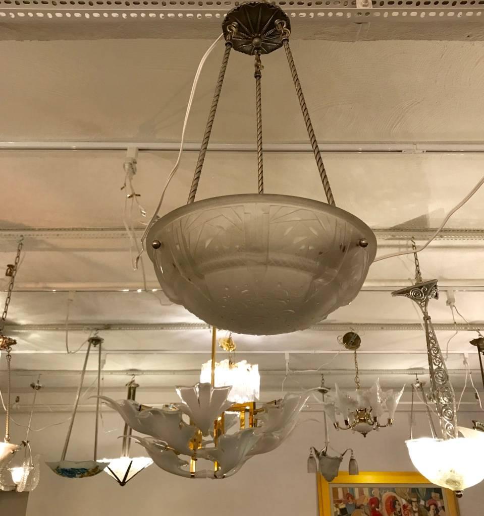 Beautiful French Art Deco geometric chandelier signed by Muller Frères. The centre glass bowl having geometric motif and deco details throughout. Supported by three design rods with a matching canopy in nickel. Re-plating upon request.


  