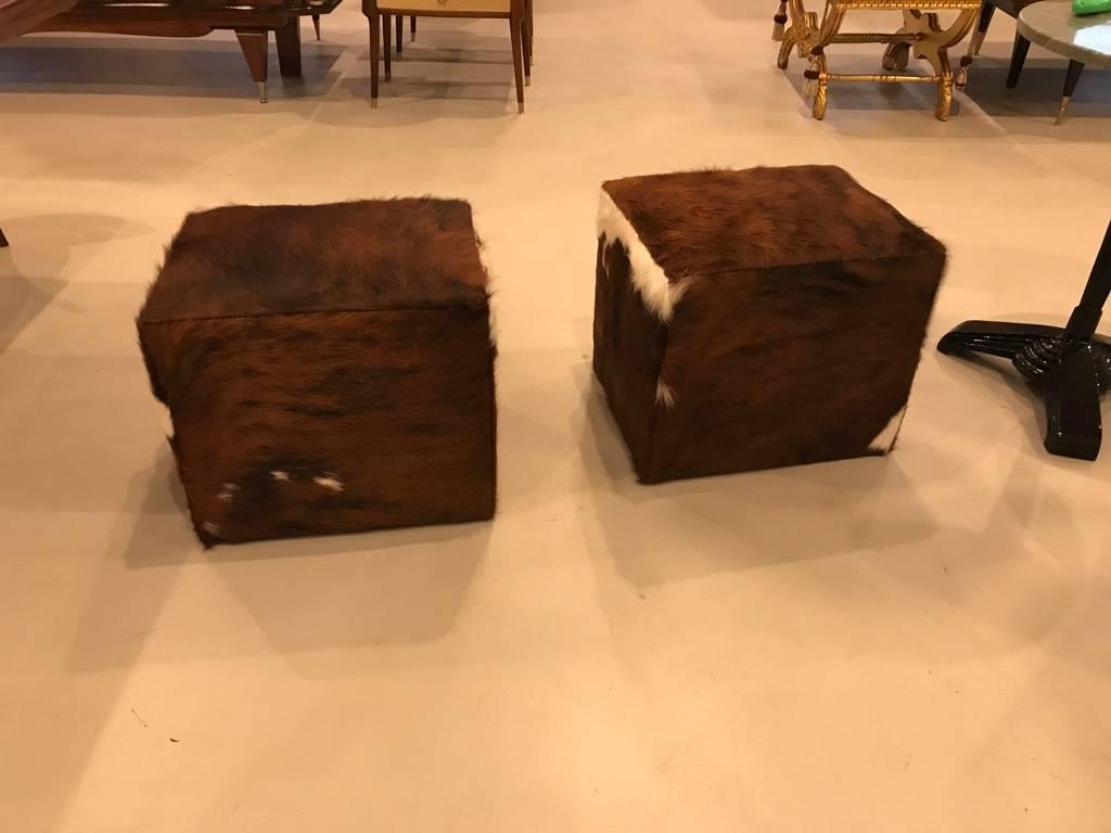 Beautiful pair of modern benches upholstered with cow hide. These ottomans have been re upholstered in cowhide.