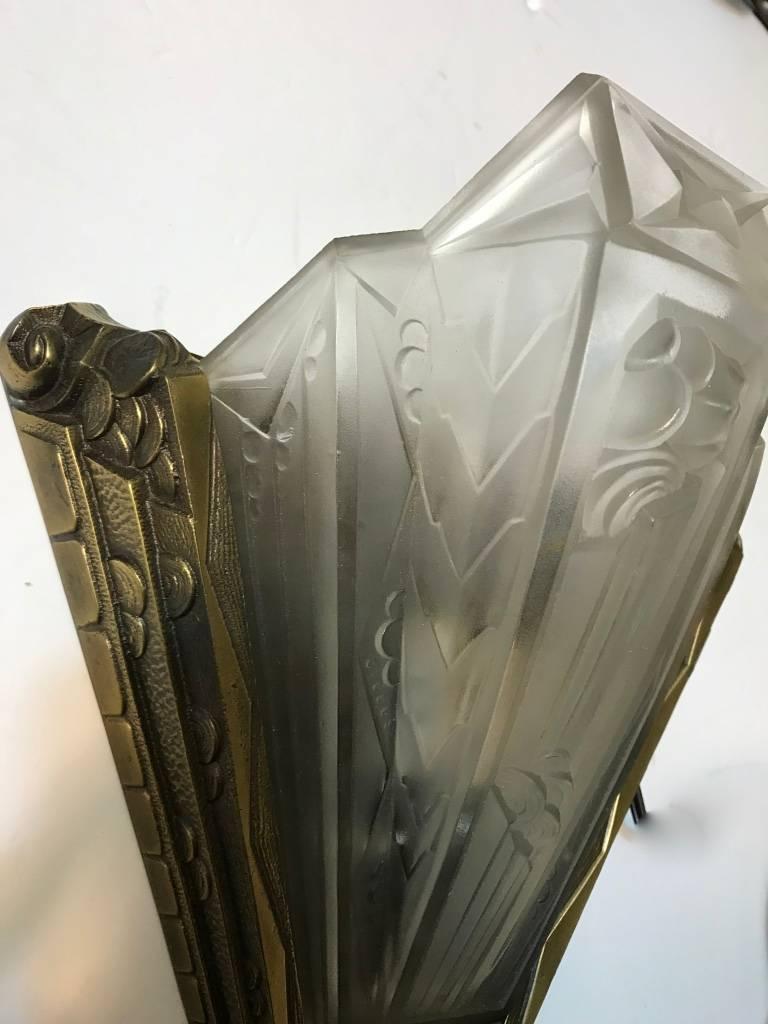 Pair of French Art Deco geometric sconces signed by Gilles. Having clear frosted glass with geometric and floral motif details. Each shade is signed Gilles. Supported by matching floral and geometric brass frames. Re-plating upon request.