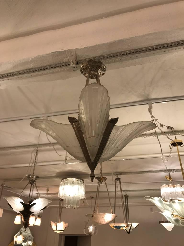 Stunning French Art Deco chandelier by E.J.G. Having four clear frosted glass shades with intricate geometric motif. With matching silver frame with beautiful geometric deco details. Re-plating upon request.