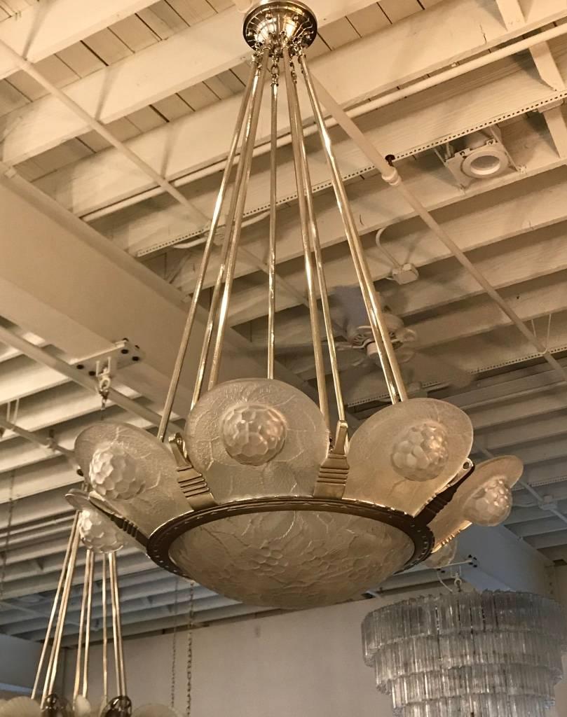 Stunning French Art Deco geometric chandelier by Simonet. Having eight panels with a center coupe bowl in clear and frosted molded glass having geometric motif. Held by a nickeled bronze geometric design frame. The frame has been plated in nickel