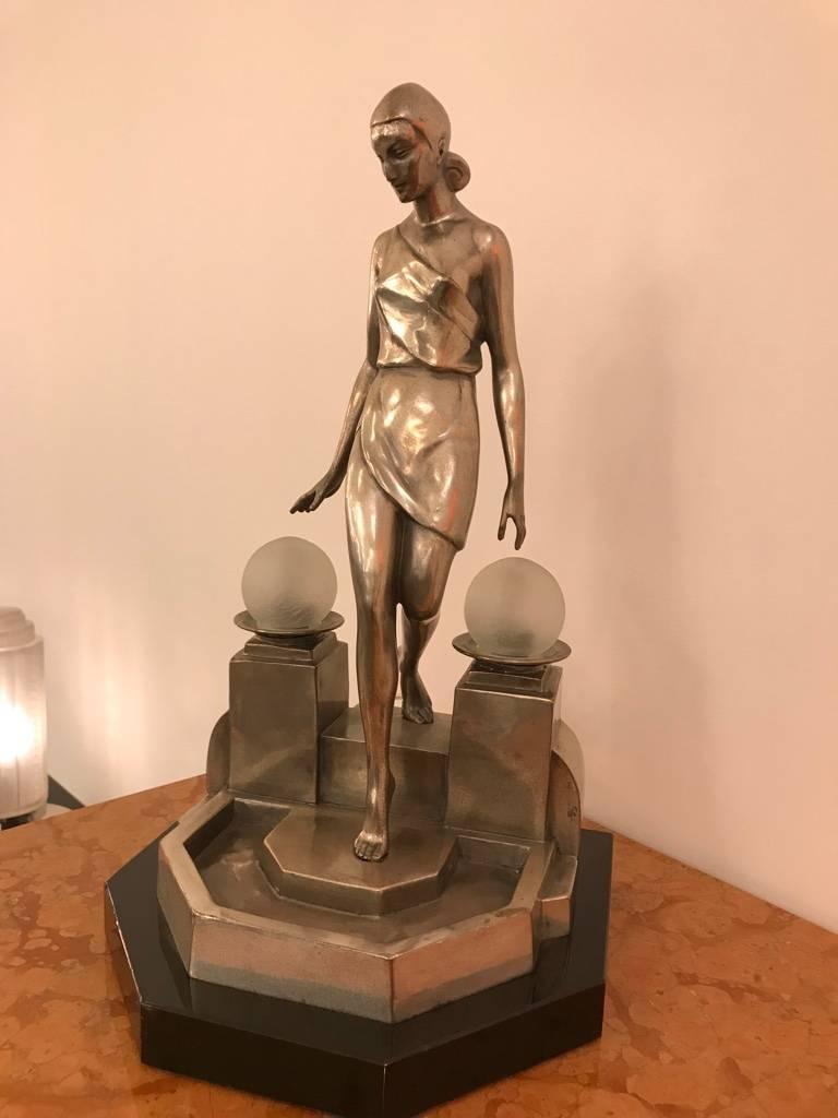 Beautiful Art Deco bronze table lamp signed by Fayral. Having female bronze on black marble base. The sculpture has two glass spheres on either side of her that illuminate.. Incredible deco details.
 
 