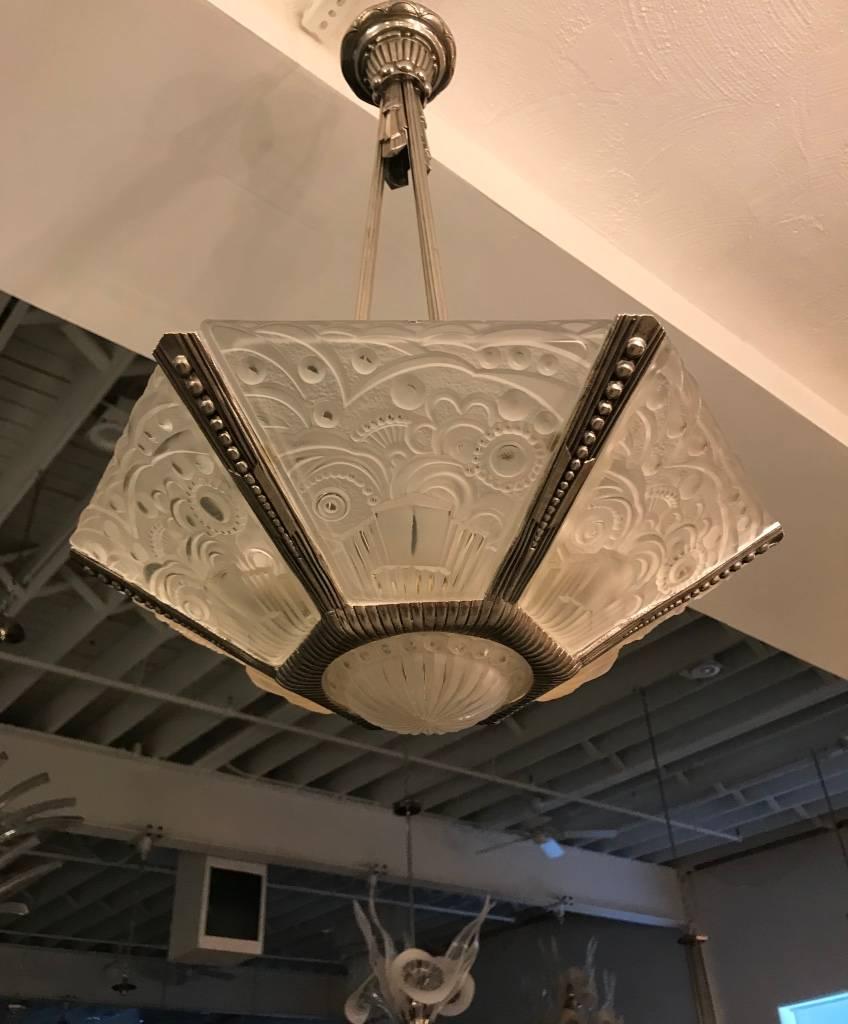 Stunning French Art Deco chandelier by Georges Leleu. With beautiful center bowl and six clear frosted glass outer panels with geometric motif. Having a matching cast bronze frame with geometric motif. Re-plating upon request.