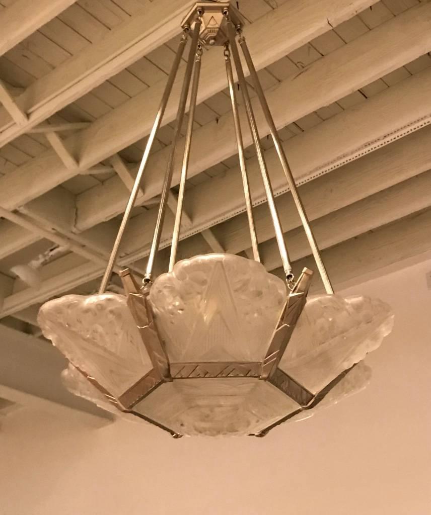 Gorgeous French Art Deco chandelier with six outer clear frosted molded glass panels and beautiful center bowl having floral motif. Polished details on a silvered nickel bronze frame with a geometric design continuing to the ceiling plate. Giving
