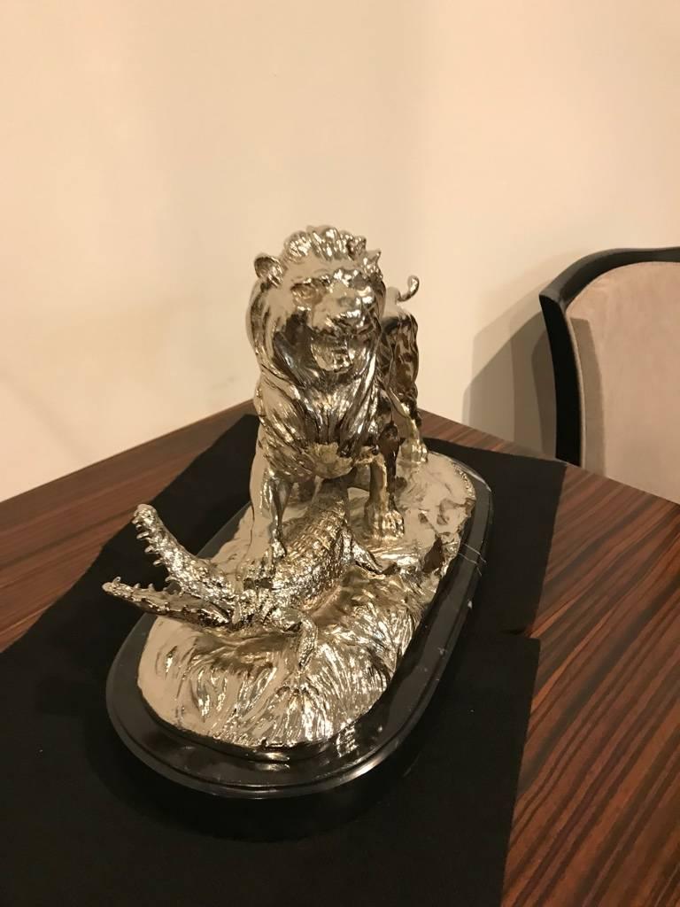 Stunning French polished nickel bronze sculpture of ferocious lion standing on alligator signed E Delabrierre. Sitting on a black marble base with incredible details.