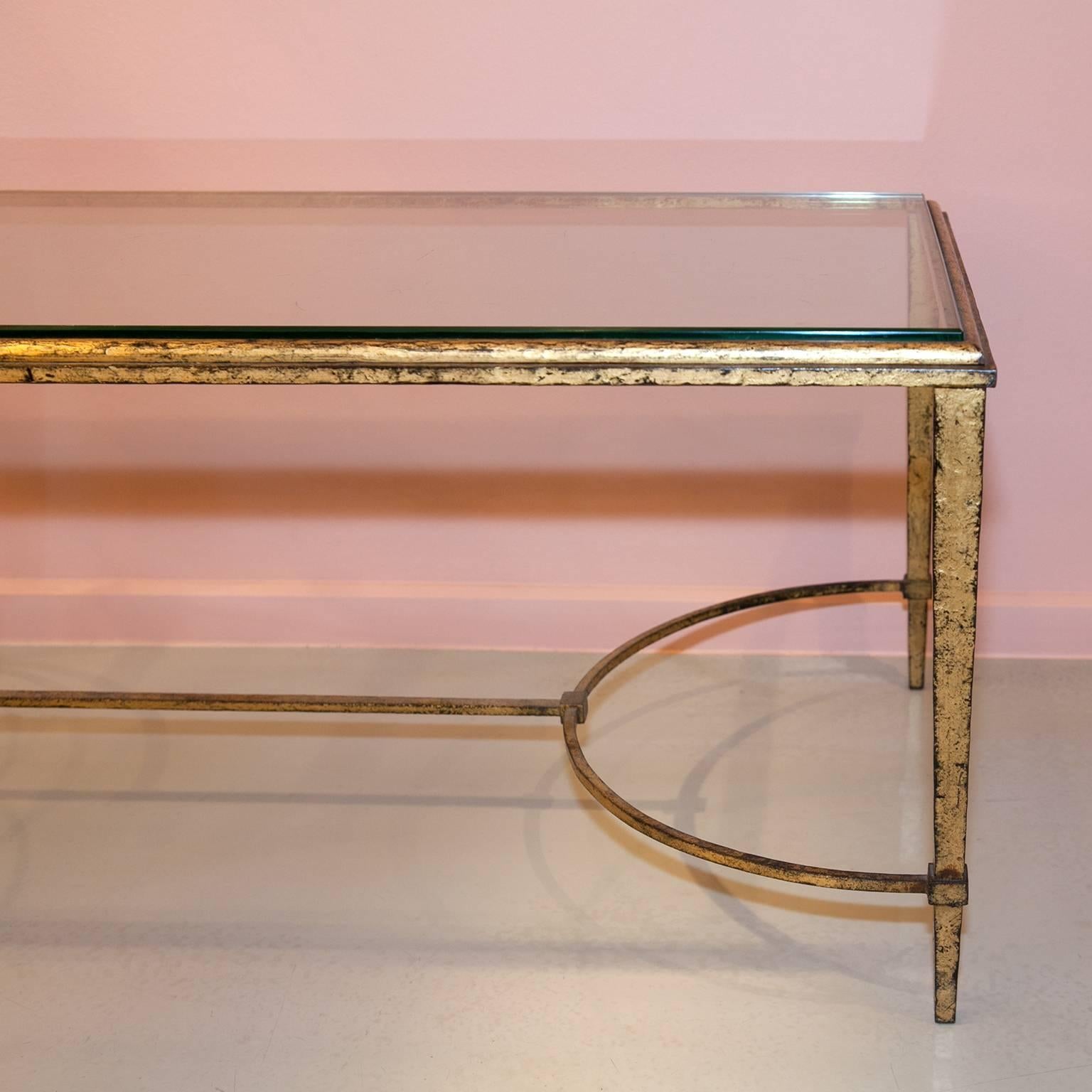 This antique coffee table is both – a truly timeless piece and a fine eye catcher for your place.
The gilded legs have a tapered shape and are connected by a thin stretcher. The glass plate features beveled edges whereby it blends perfectly into the