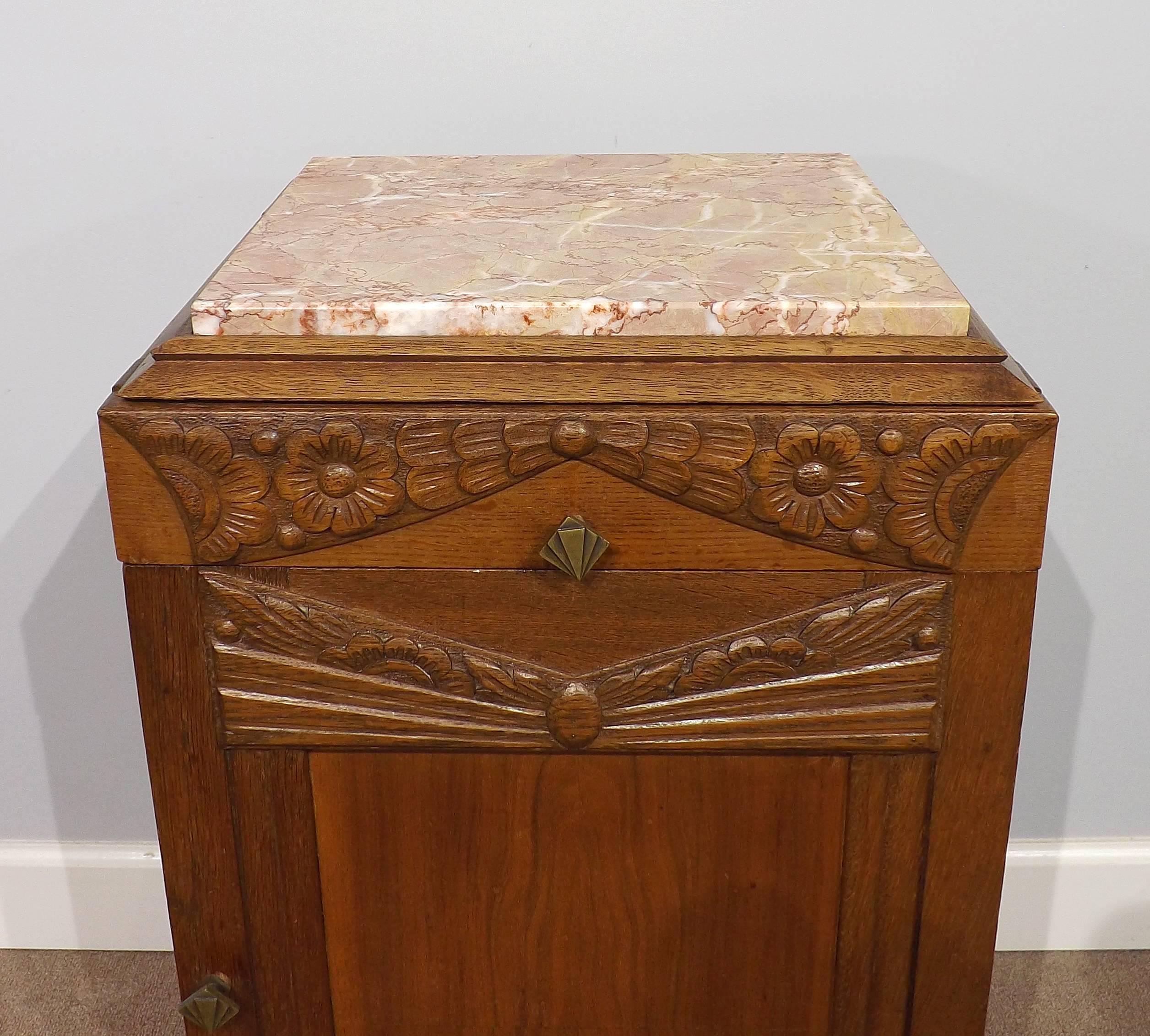 A gorgeous pink marble top Art Deco oak cabinet from the 1930s, with original ornate hardware and wonderful floral carving.