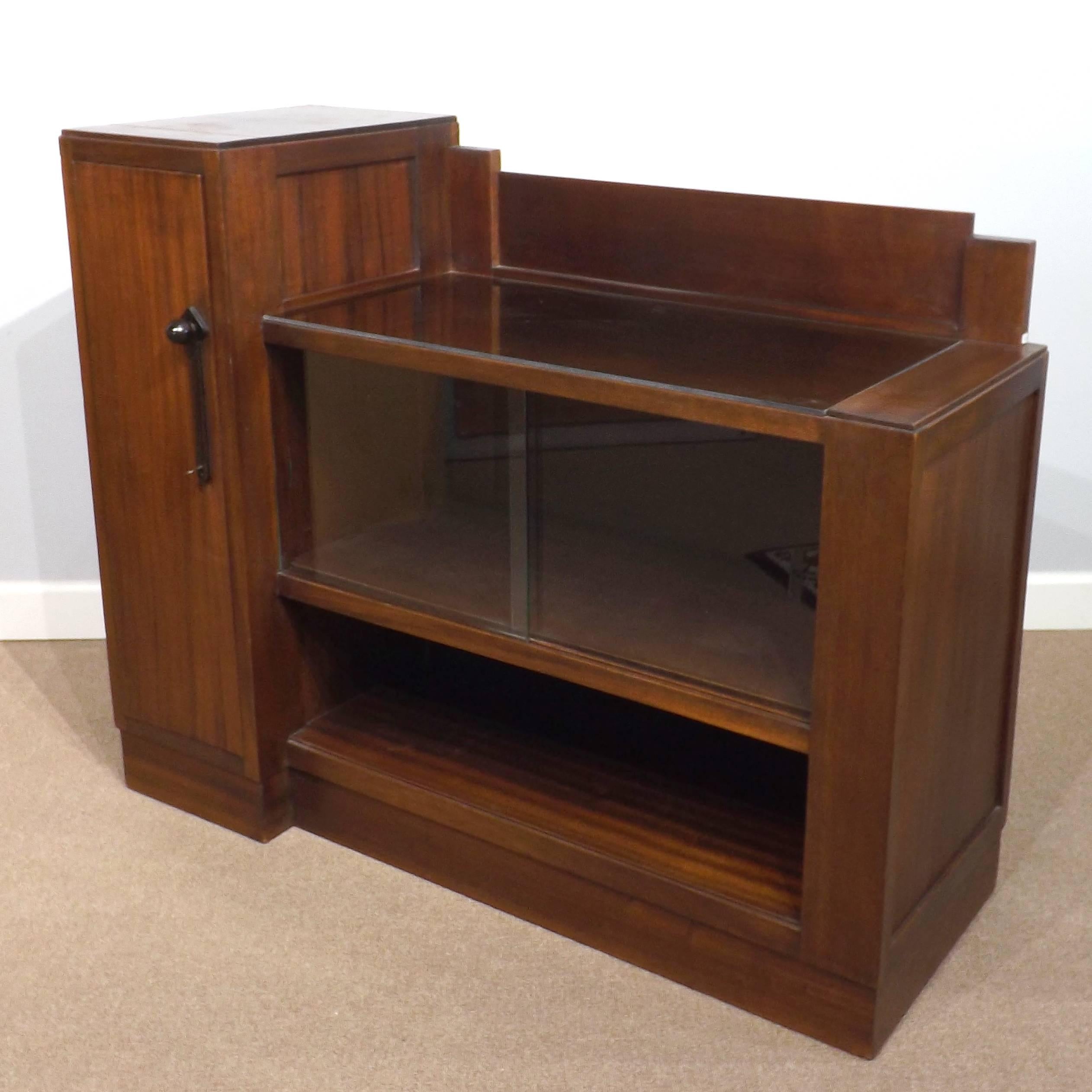 A fine dry bar or liquor cabinet suitable for entertaining in a small room in the Art Deco style, from the 1920's. With sliding glass doors, and a serving area covered with glass in case of spills. Side door has an styled macassar ebony pull and