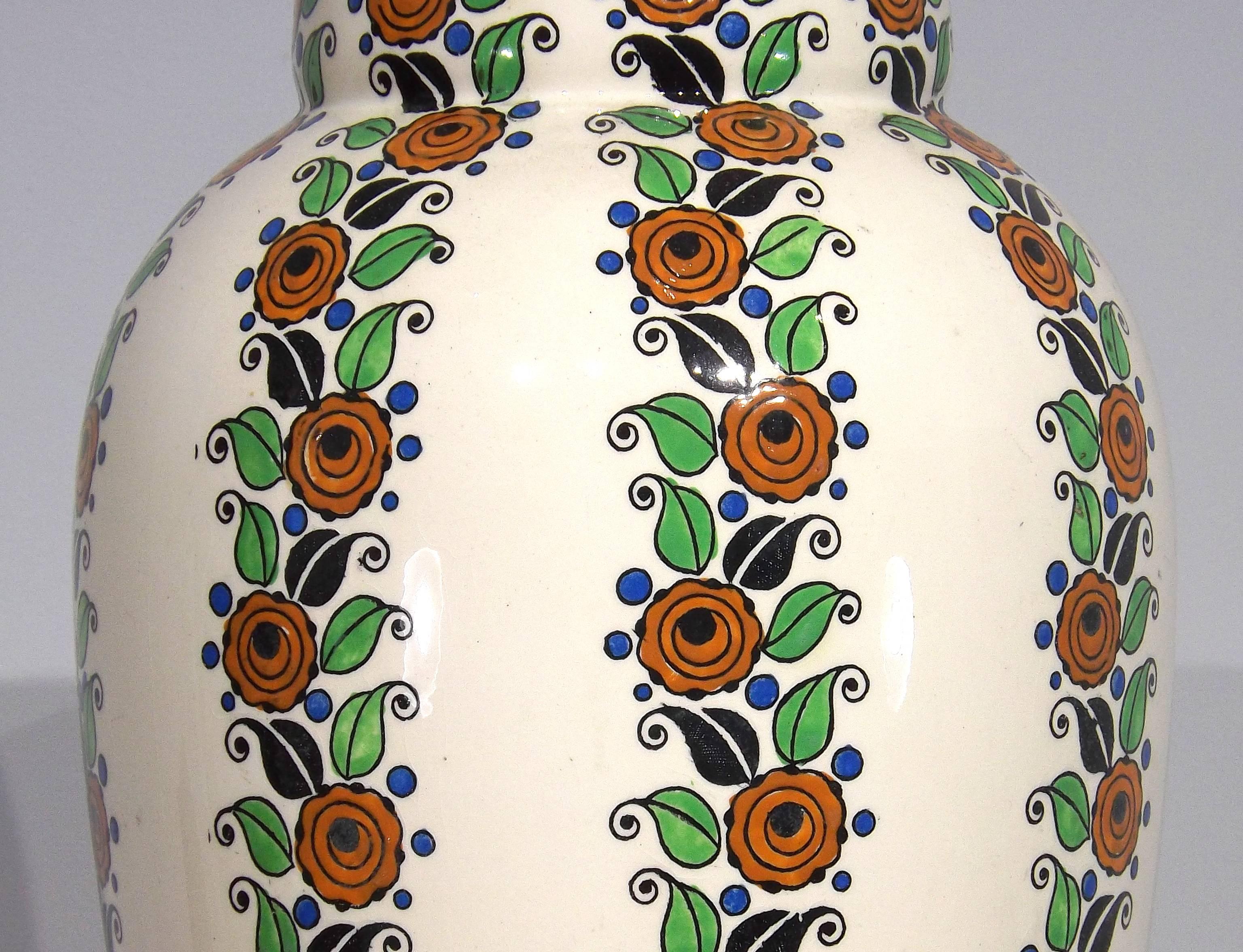 A tall vase covered with ascending rows of flowers made by the famous Boch Freres pottery from Belgium. Stamped on bottom with their company logo.