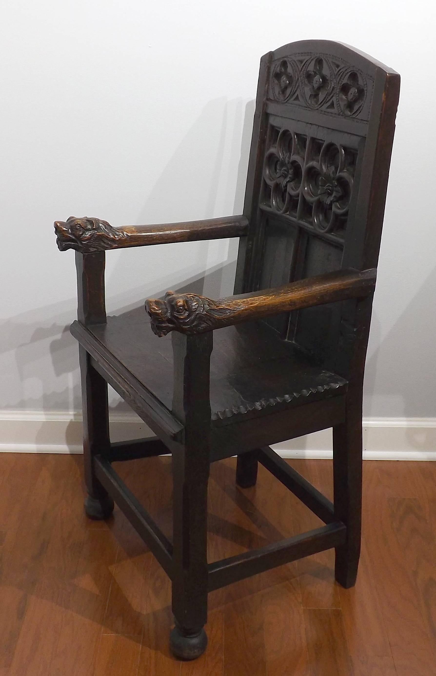 An incredibly old carved wooden chair with Gothic tracery back, dating from the early 1600s or earlier. Magnificent carved animal head armrests.