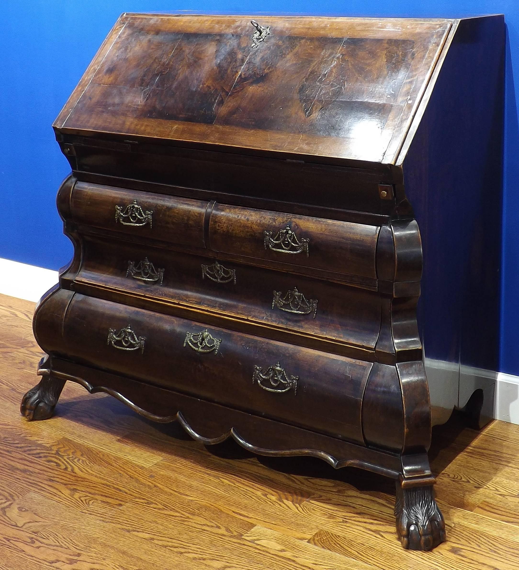 A handsome double bowed drop front desk with carved claw and ball feet dating from the 18th century. The bottom has four spacious drawers while the folding writing surface closes to protect numerous smaller drawers and a number of secret