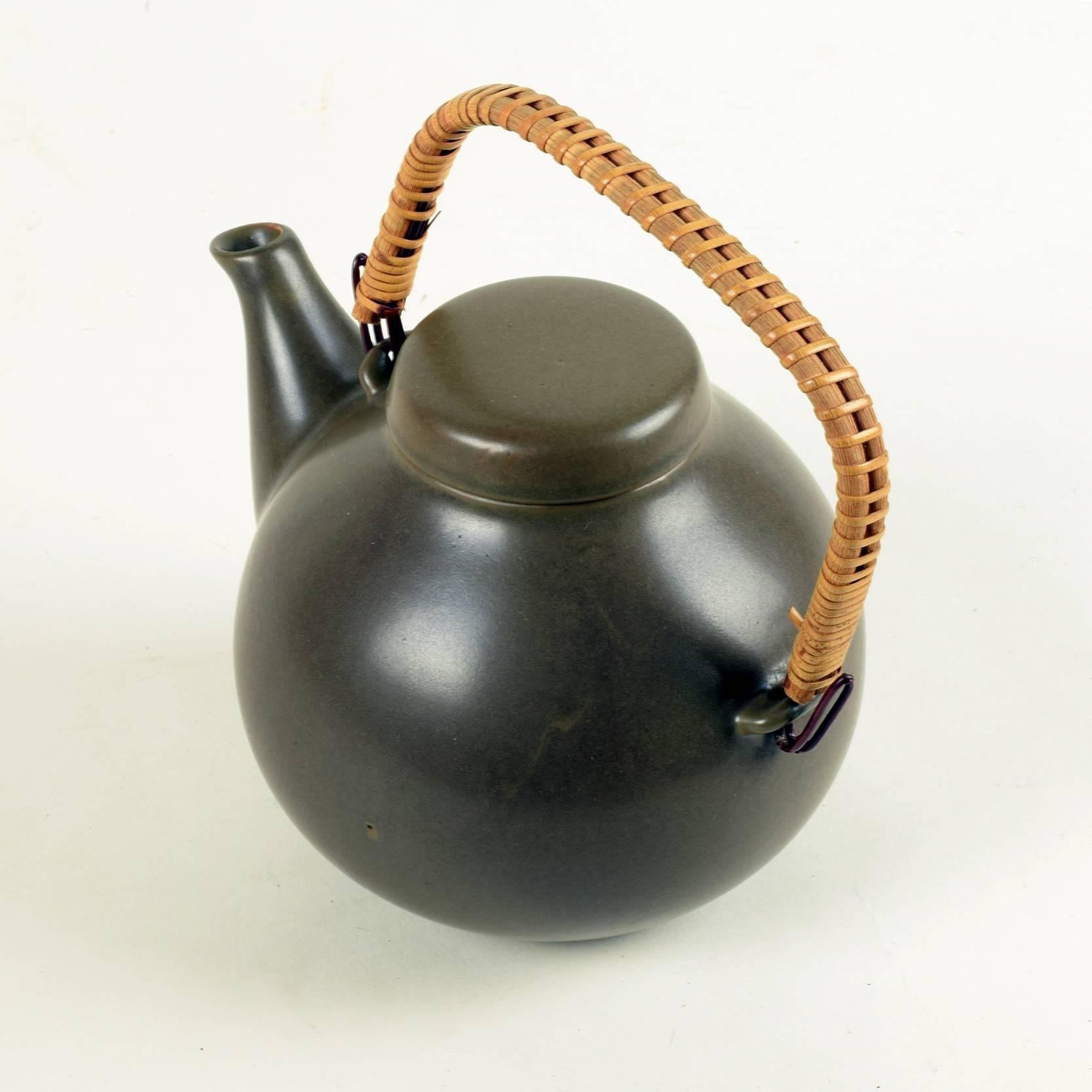 Ulla Procopé for Arabia Finland
Large GA3 teapot, designed 1953, manufactured from 1955-1972.
Fired and glazed earthenware, brown finish, rattan handle.
Good condition with minor signs of wear.

Dimensions excl. handle: Height 16cm (61/4 in),