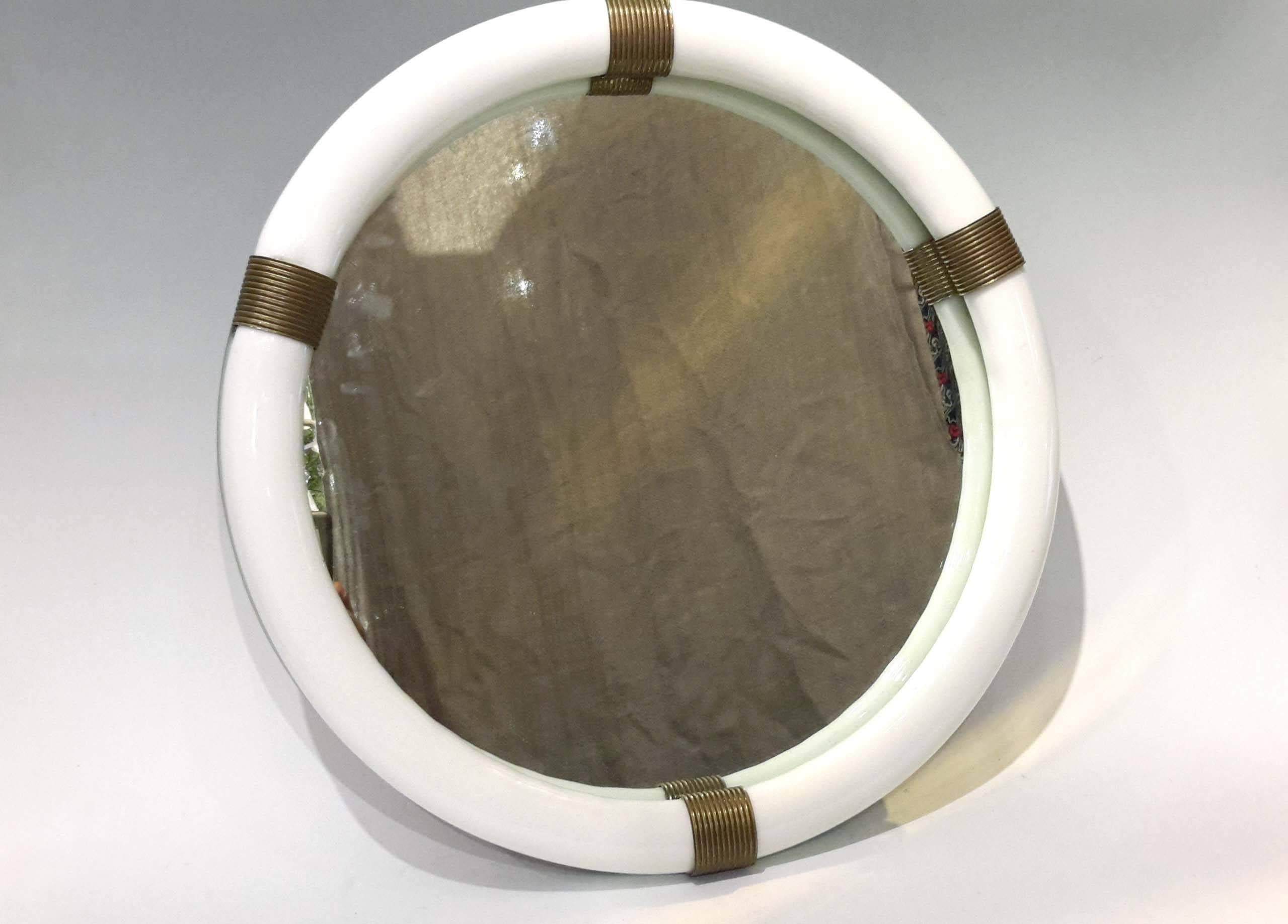 16.50 inches in diameter, 1.25 inches deep
A vintage Venini handblown Murano opaline glass framed round wall mirror with bronze decorative accent.