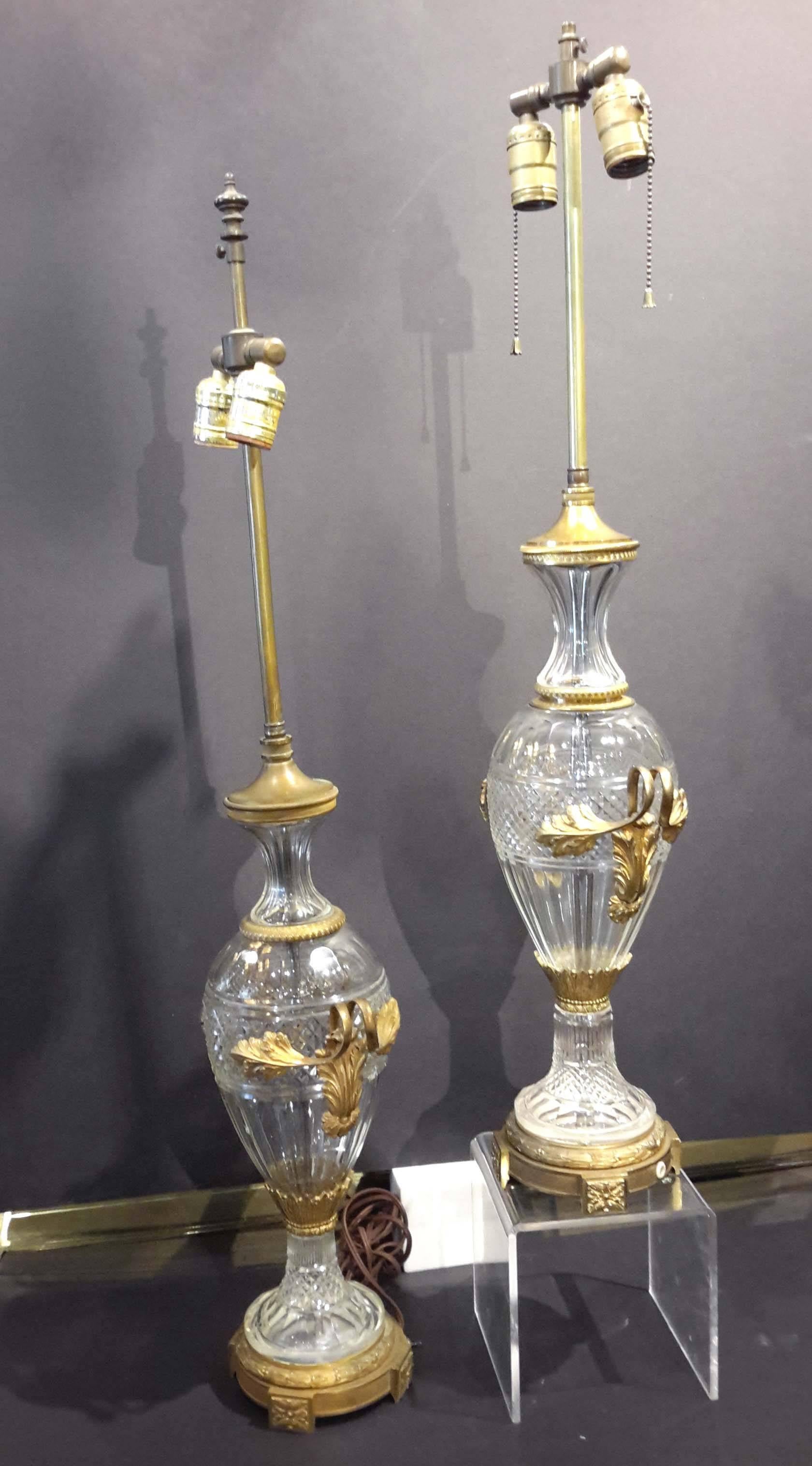 They are almost a matching pair, except for two bronze fitting, one in the neck and one in the top. Cut crystal and gilt bronze.

One lamp is 32 inches high. The other is 34.25 inches high.
Width is 8.50 inches.
Depth on both are 5 inches.