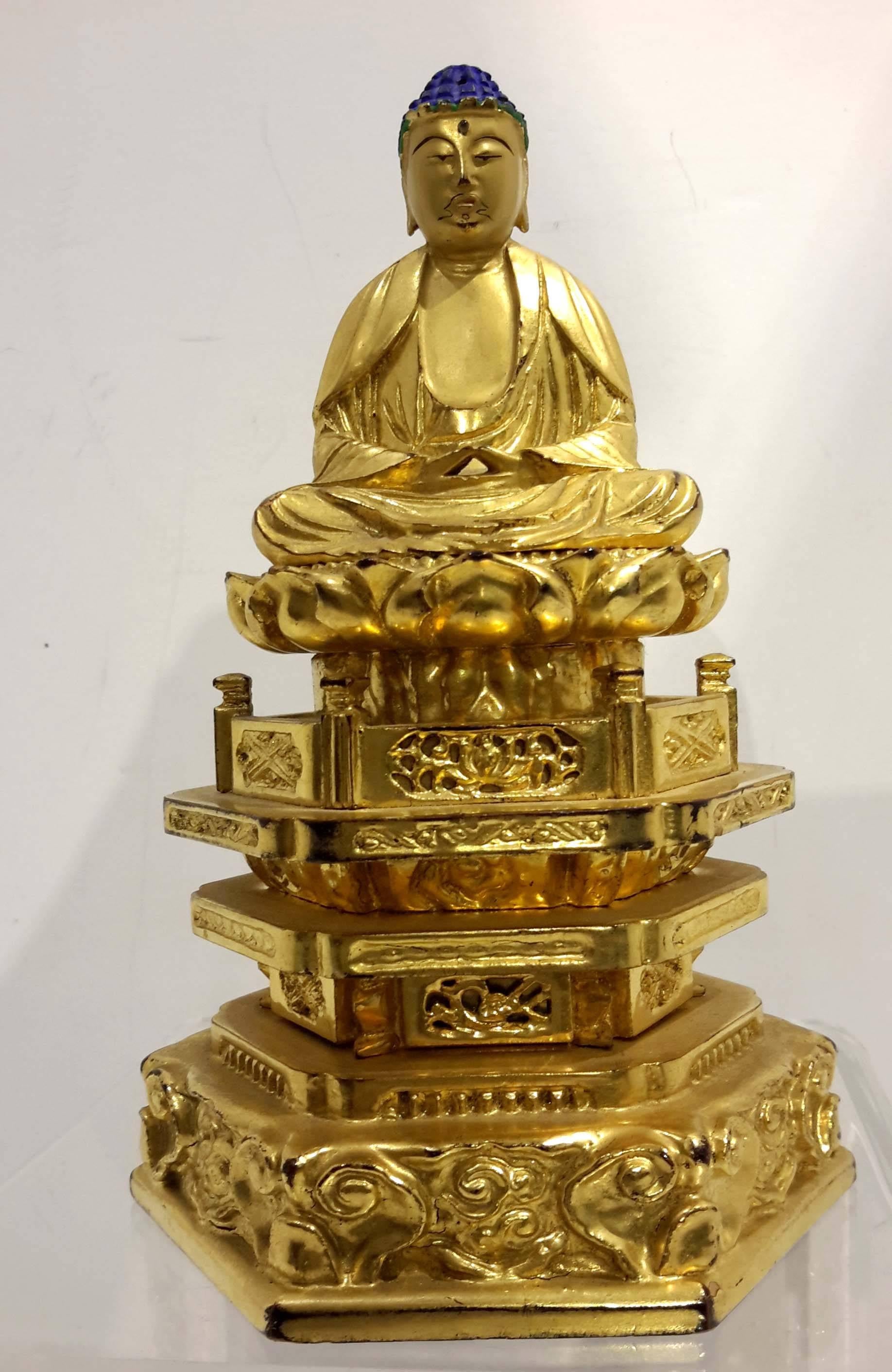 Beautifully gilded carved wood. This Buddha probably belonged in a traveling shrine at one time. Original lapis color paint on the top of the head.