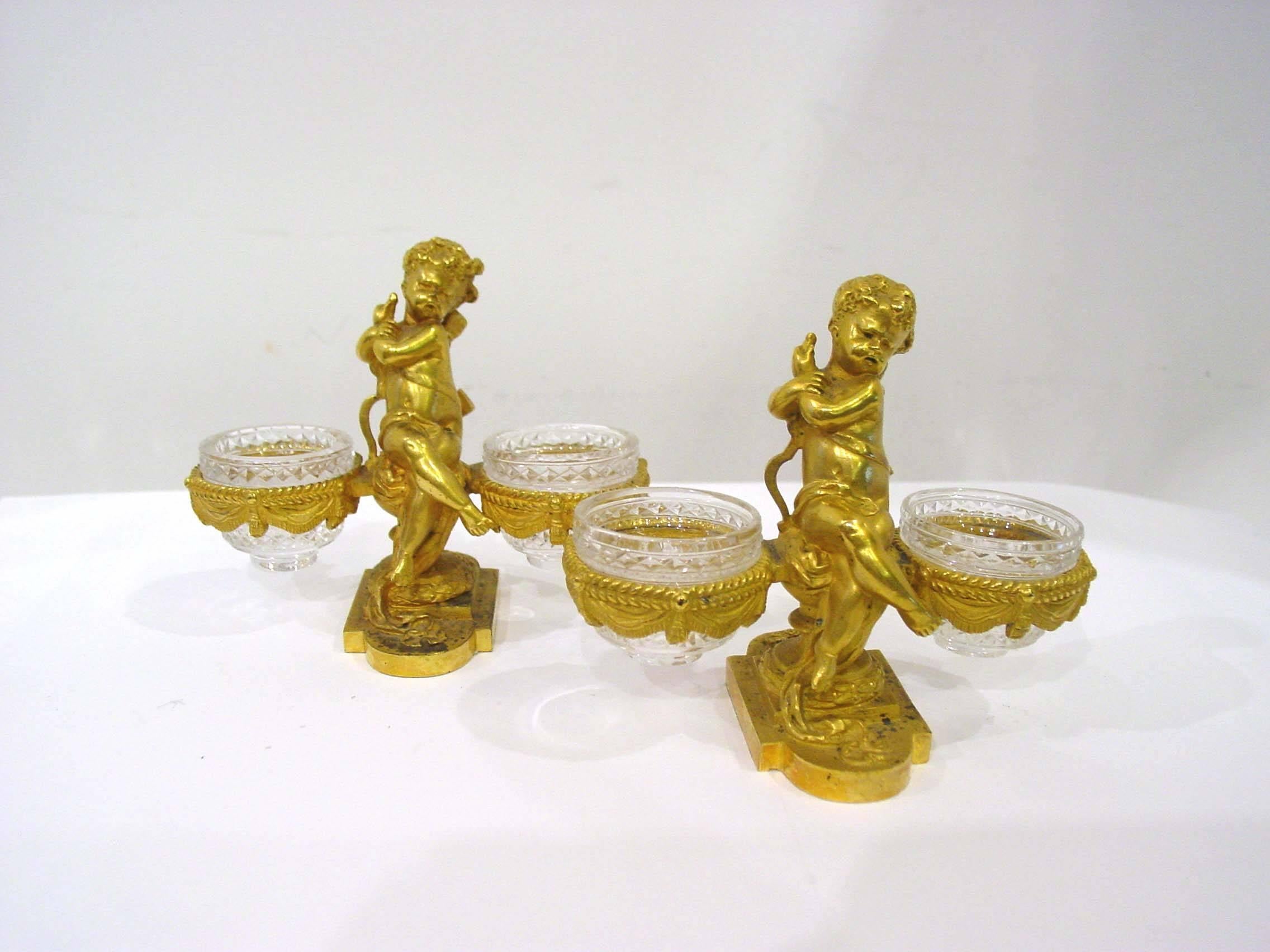 Great ensemble set signed Baccarat, consisting of pair of figural open salt cellars and figural gilt bronze vase holder.
The gilt bronze pieces with exquisite details. the crystals beautifully carved. All pieces have Baccarat stamp under the bronze