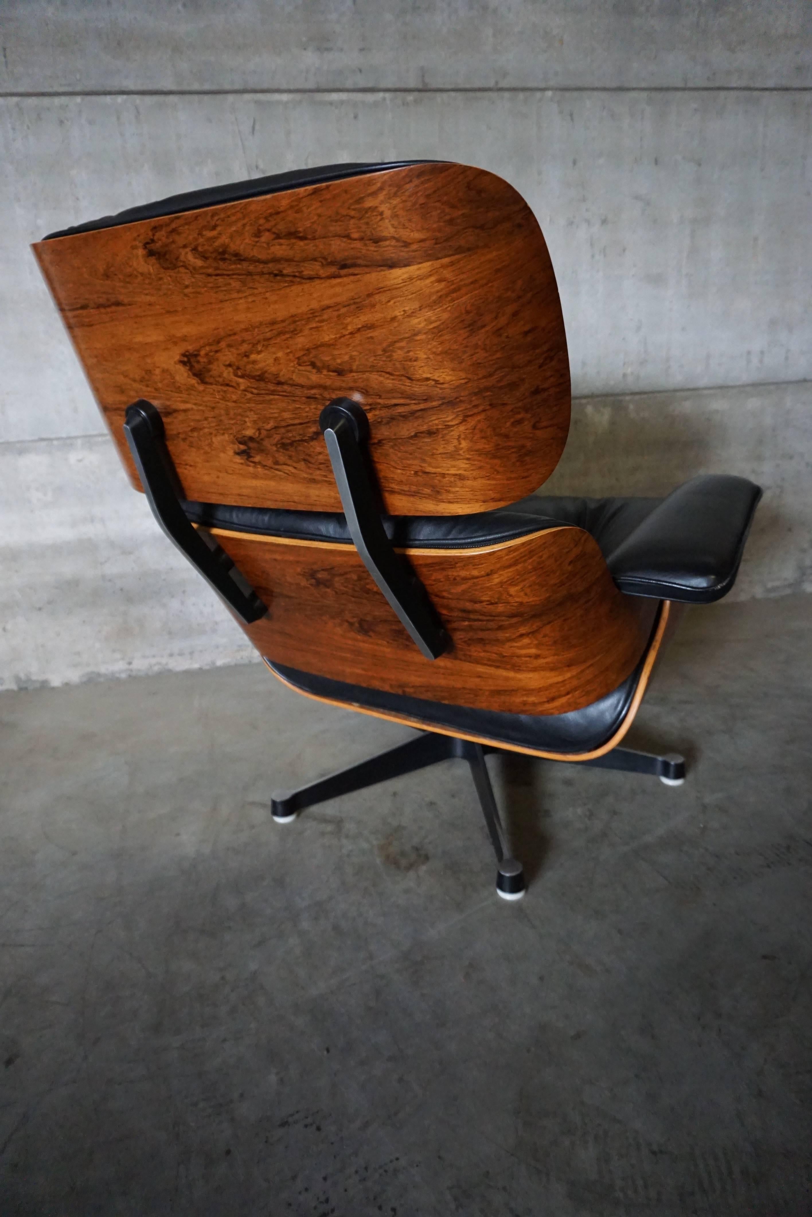 This Mid-Century lounge chair model 670 was designed by Charles and Ray Eames and produced by Vitra in the 1970s. They feature rosewood veneer moulded plywood seat shells and leather-covered cushions resting on a cast aluminium base. This set