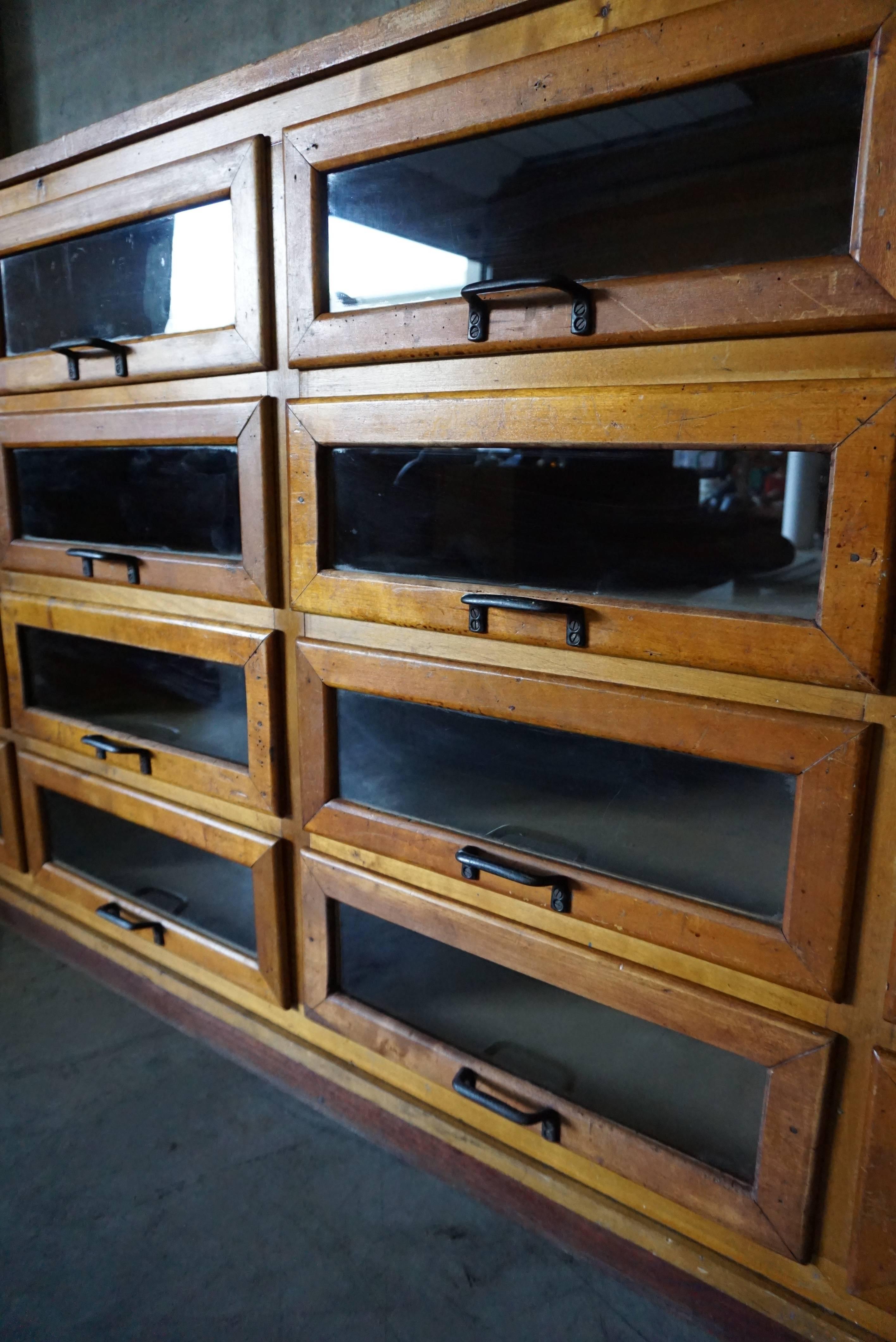 This vintage haberdashery shop cabinet originates from the United Kingdom. It is made from wood and features 16 glass fronted drawers. The cabinet is in a good vintage condition with the drawers opening and shutting smoothly.