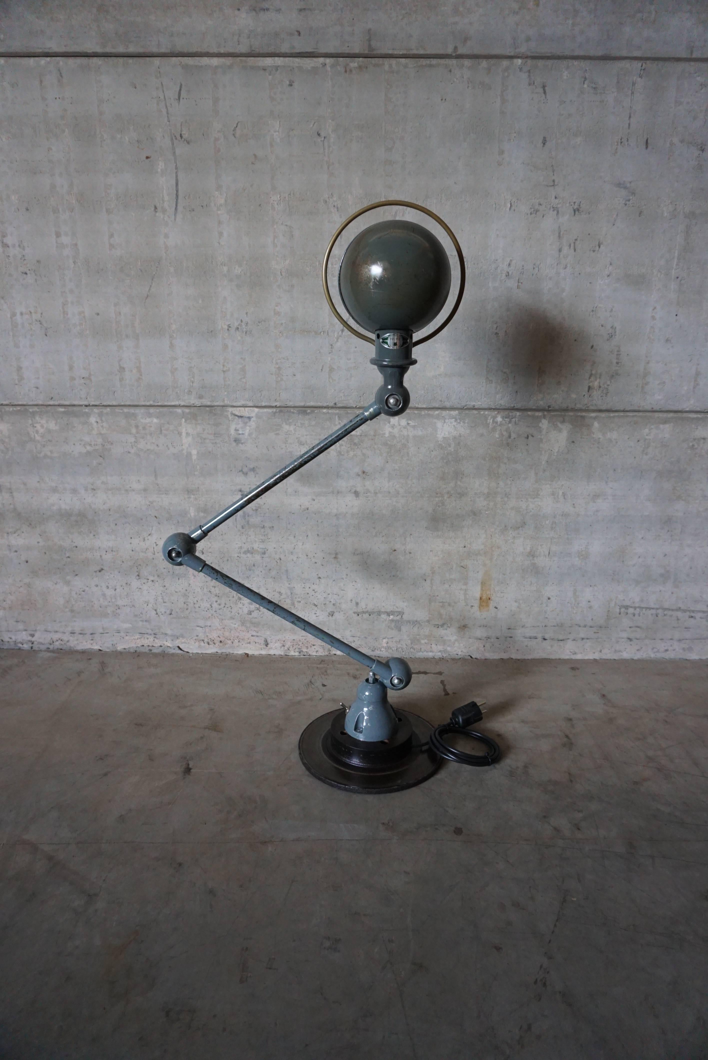This Industrial lamp was manufactured by Jieldé in Lyon, France during the 1950s. The lamp is mounted on a clean brake disk. It features an articulated arm composed of two adjustable parts of 40 cm length each. The lamp has been fully restored, and