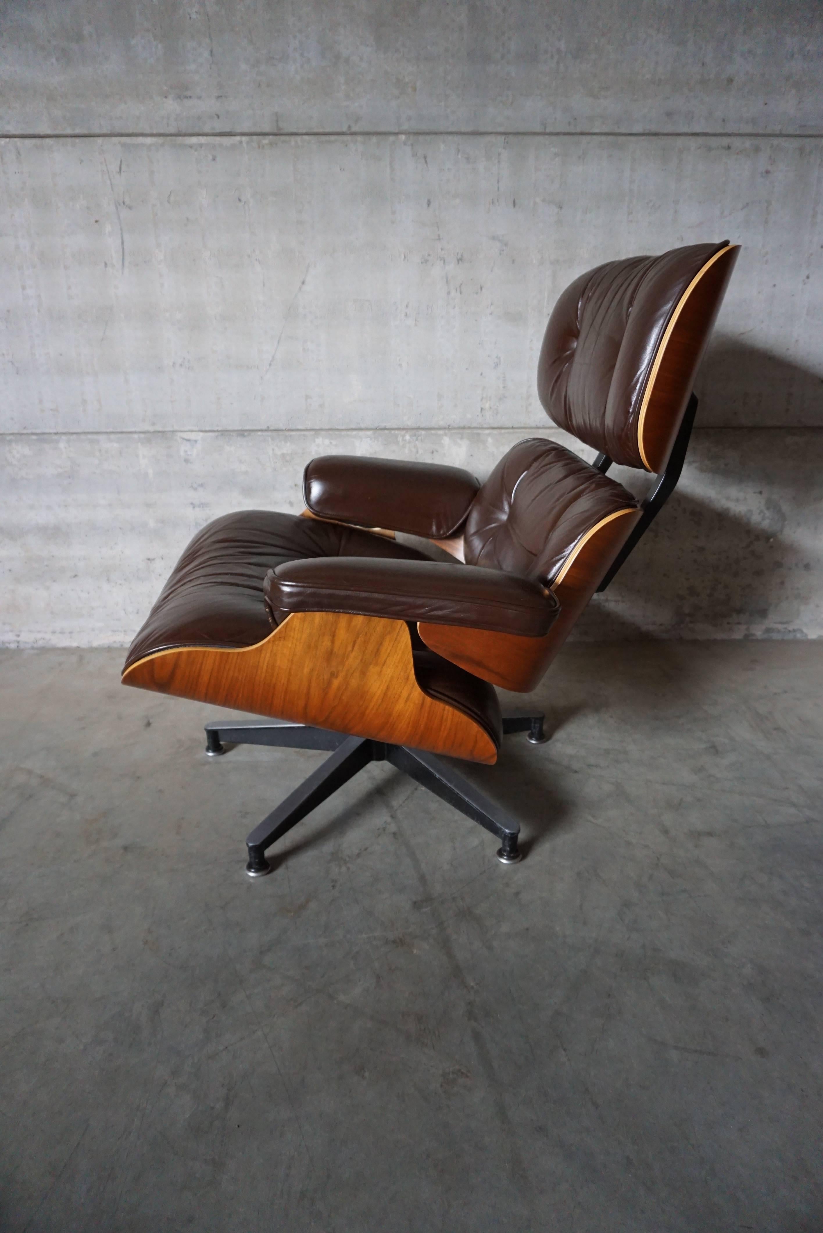 This model 670 lounge chair was designed by Charles & Ray Eames in 1956. This chair was produced in the 1990s by Herman Miller. They feature walnut veneer moulded plywood seat shells and dark brown leather-covered cushions resting on a cast